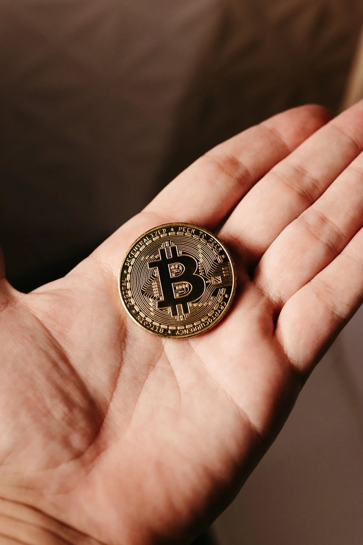 Single Bitcoin coin resting in an open palm