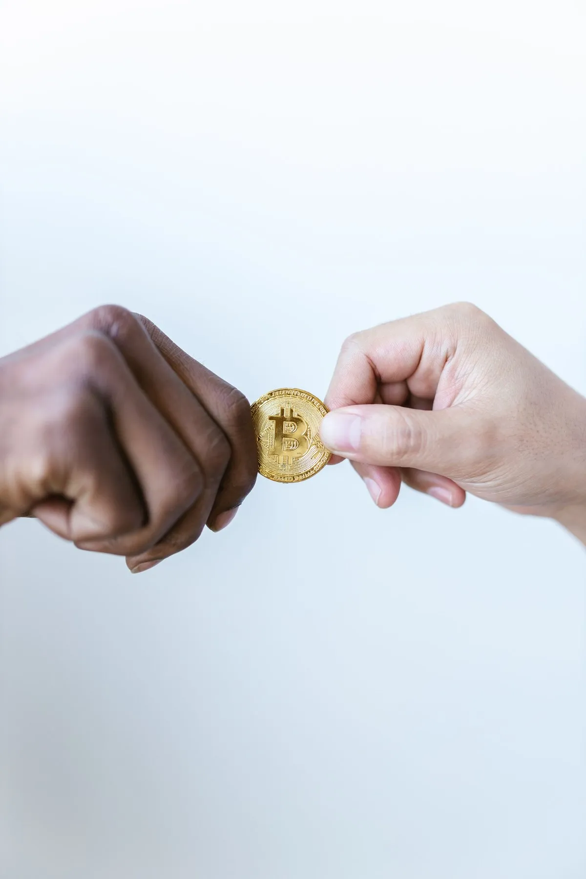 One hand passing a Bitcoin coin to another